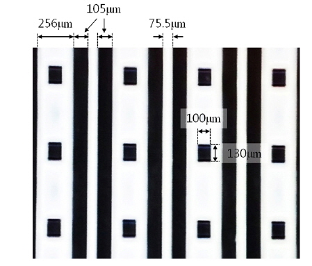 The microscopic image of the reflective white pattern having bars of width 75.5 μm and bars of width 256 μm containing rectangular apertures of size 100 × 130 μm.